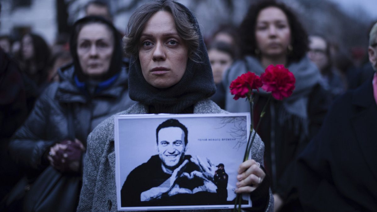 A woman holds flowers and a portrait of opposition leader Alexei Navalny during a protest in front of the Russian embassy in Berlin, Germany, Friday, Feb. 16, 2024. 