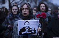 A woman holds flowers and a portrait of opposition leader Alexei Navalny during a protest in front of the Russian embassy in Berlin, Germany, Friday, Feb. 16, 2024. 