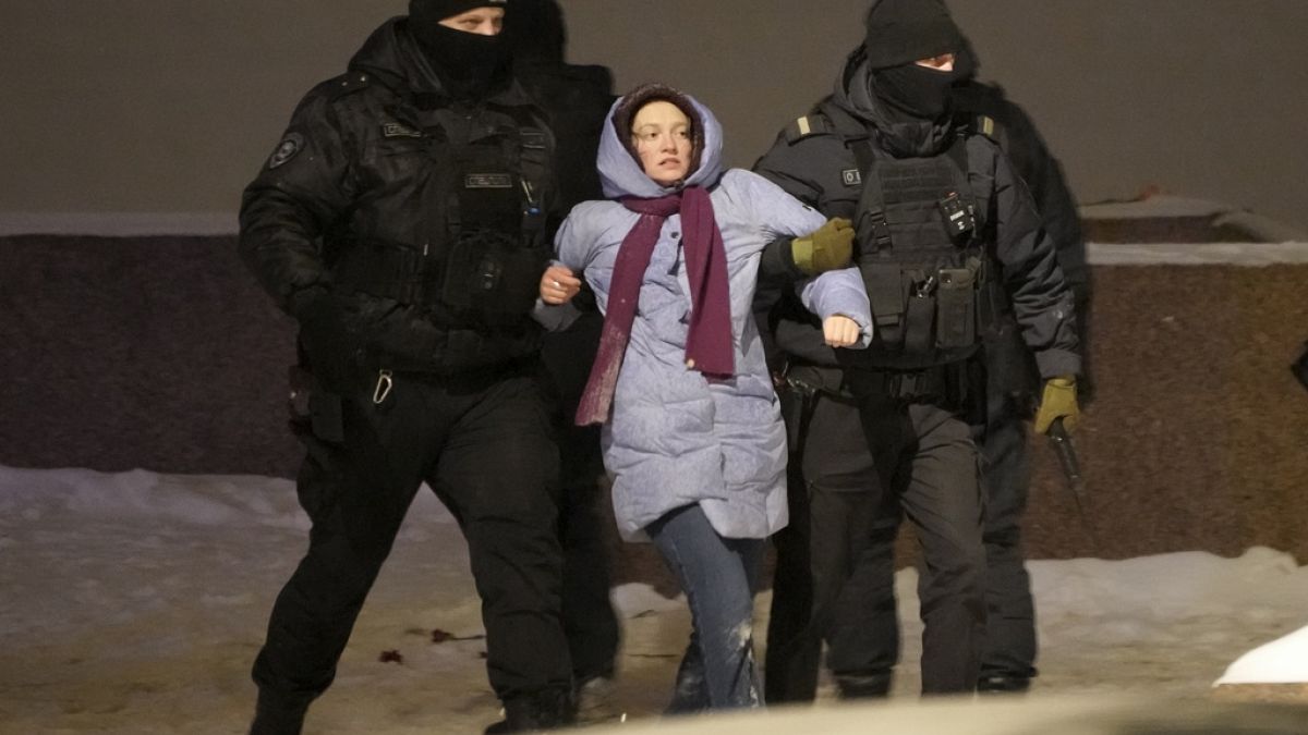 Police officers detain a woman who laid flowers for Alexei Navalny at the Memorial to Victims of Political Repression in St. Petersburg, Russia