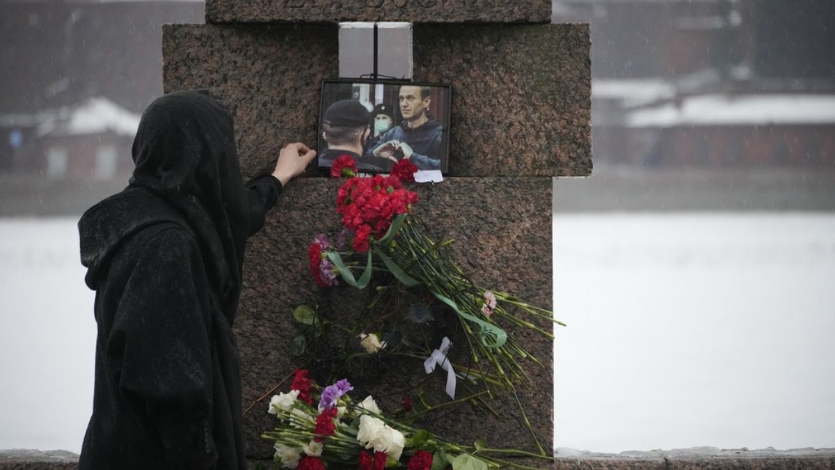 Una mujer toca una foto de Alexéi Navalni tras depositar flores para rendirle un último homenaje en el Monumento a las Víctimas de la Represión Política en San Petersburgo.