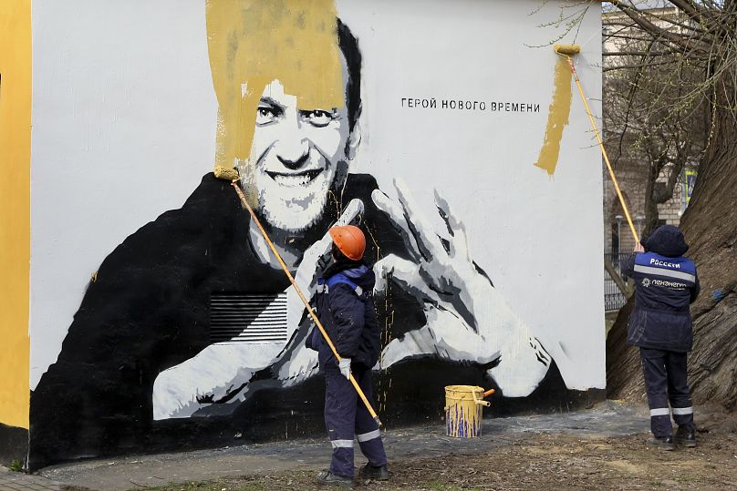 کارگران شهرداری سن‌پیترزبورگ در حال محو کردن عکس ناوالنی از روی یک دیوار در سال ۲۰۲۱