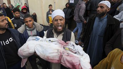 فلسطيني يحمل جثمان طفله أمام ستشفى الأقصى في دير البلح
