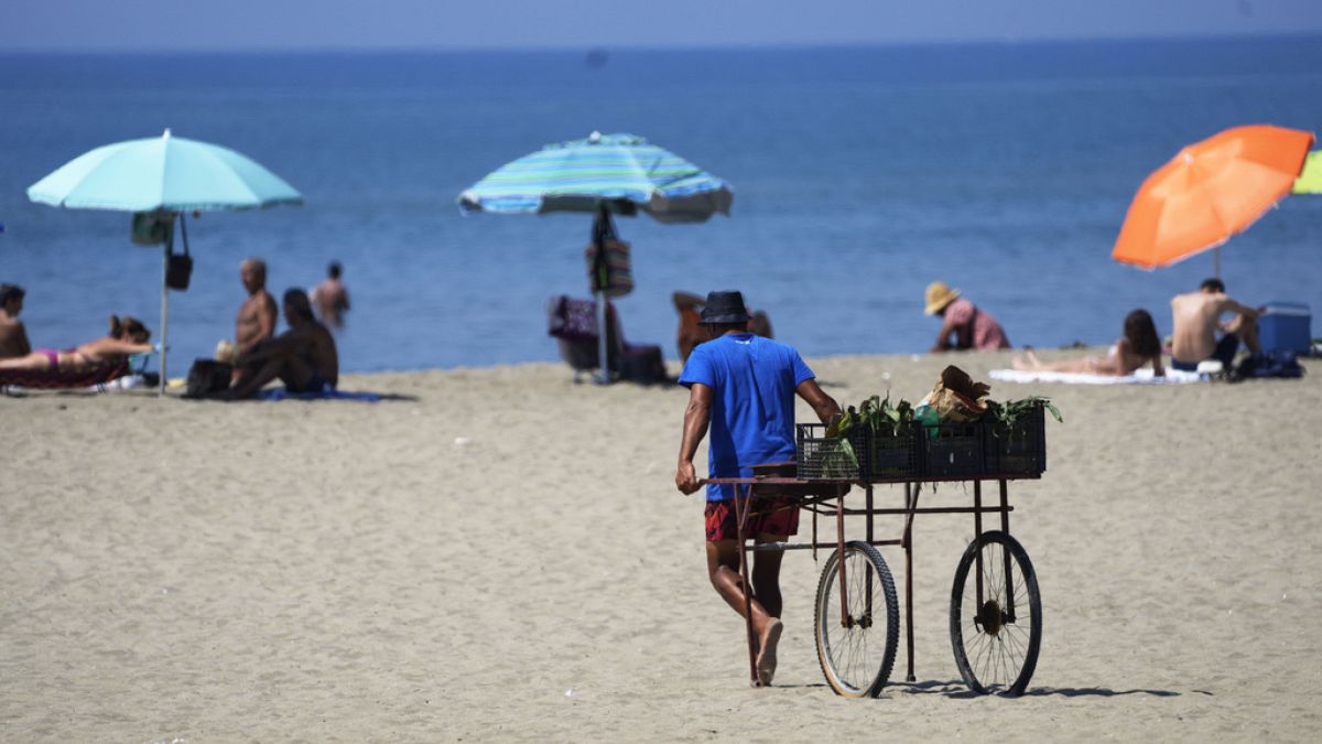 Пляжный торговец везет свою повозку на пляж в Остии, недалеко от Рима, 23 августа 2023 года