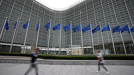 European Union flags wave in the wind as pedestrians walk by EU headquarters in Brussels, on Sept. 20, 2023. 