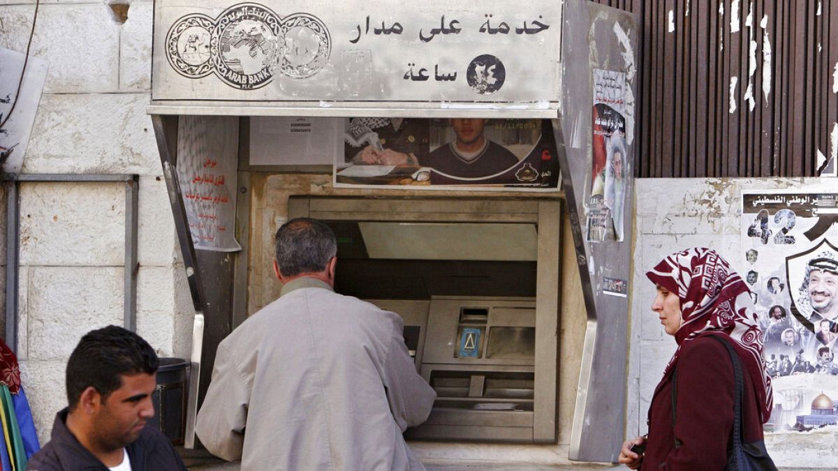 İsrail işgali altındaki Batı Şeria'nın Ramallah kentinde bir ATM'den maaş çeken Filistinliler (arşiv) 