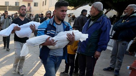 فلسطينيون بالقرب من مستشفى الأقصى يحملون جثامين أطفال قتلوا في قصف إسرائيلي في قطاع غزة