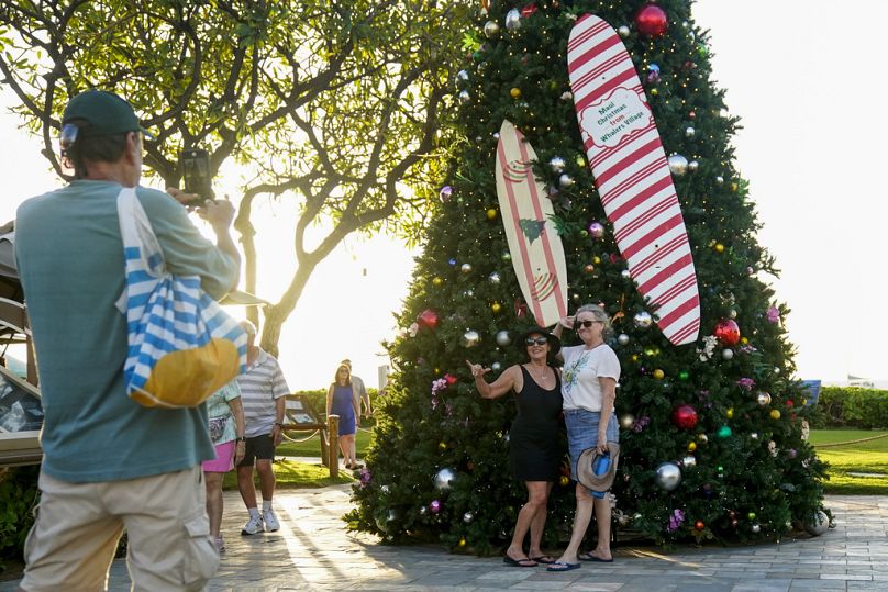People pose for a photo in front of a Christmas tree at Kaanapali Beach, Hawaii in December after tourists begin to return to the destination after the deadly Lahaina fires