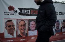 A man in Jerusalem walks past a banner with photographs of hostages who were abducted during Hamas's 7 October attack on southern Israel.