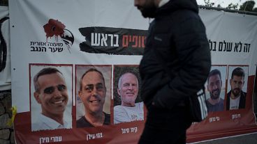 A man in Jerusalem walks past a banner with photographs of hostages who were abducted during Hamas's 7 October attack on southern Israel.