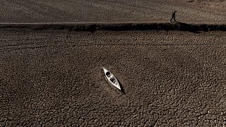 Un uomo passa davanti a una canoa abbandonata nel bacino idrico di Sau.