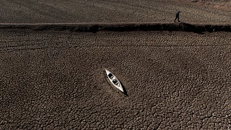 A man walks past an abandoned canoe at the Sau reservoir.