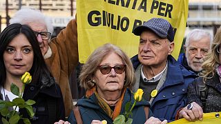 Gulio Regeni'nin annesi ve Paola ve babası Giulio anne ve babası Paola ve Giulio mahkeme girişinde "Giulio Regeni için Gerçek" pankartla poz verdi.