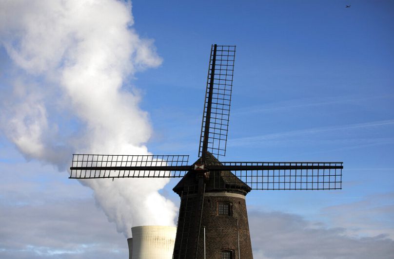 Steam rises from a nuclear power station behind an old windmill on the River Scheldt in Doel, September 2019