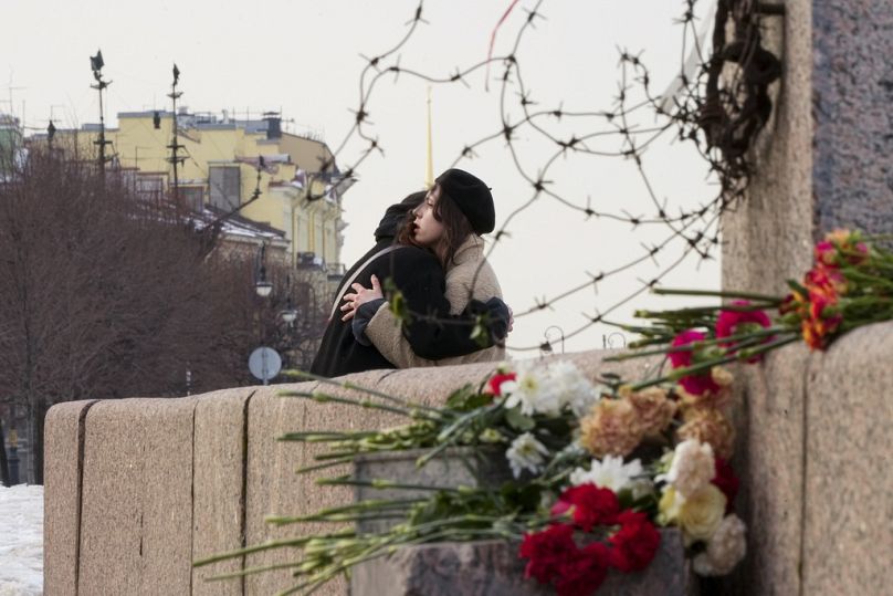 Women embrace after laying flowers at the Memorial to Victims of Political Repression to pay respect to Alexei Navalny in St Petersburg.