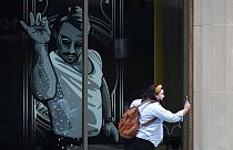 A passer-by uses a mobile device near a window featuring a likeness of chef and social media star Salt Bae outside the Nusr-Et Boston restaurant, Sept. 29, 2020.