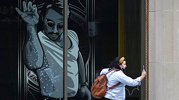 A passer-by uses a mobile device near a window featuring a likeness of chef and social media star Salt Bae outside the Nusr-Et Boston restaurant, Sept. 29, 2020.