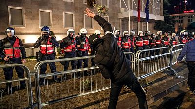 A supporter of the Albanian opposition throws flowers to police officers during a protest in front of Government building in Tirana, Albania, Tuesday, Feb. 20, 2024.