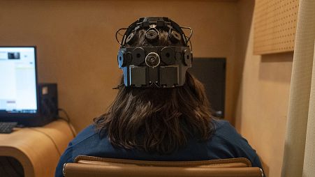 Emily Hollenbeck, a deep brain stimulation therapy patient, demonstrates an EEG device that records brain activity.