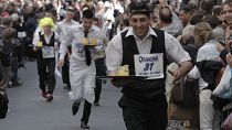 People dressed as waiters carry trays of drinks as they take part in a race through the streets of Paris.