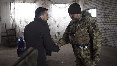 Ukrainian President Volodymyr Zelenskyy, left, shakes hand with a soldier during his visit to the front line city of Kupiansk, Kharkiv region, Ukraine, Feb. 19, 2024.