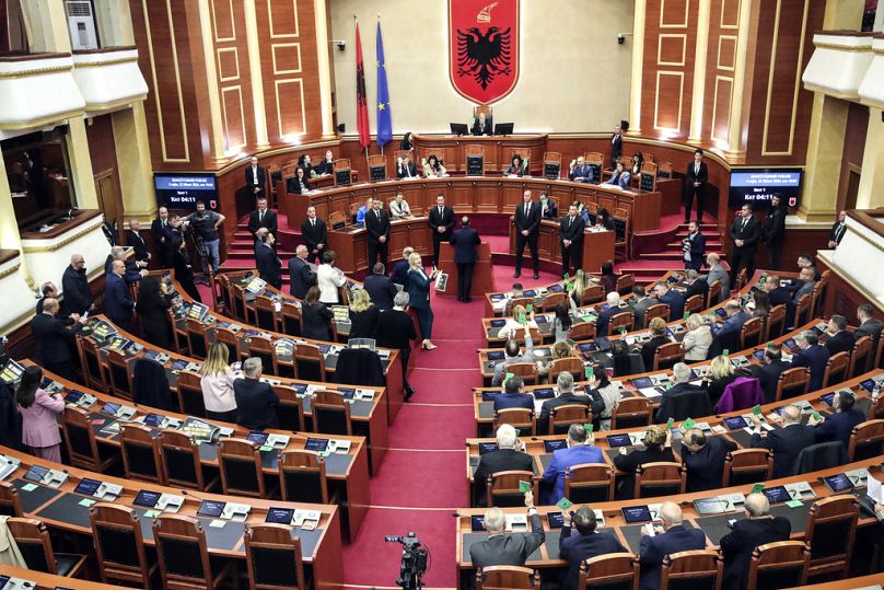 Lawmakers of Albania's Democratic Party, left, look on as their colleagues of the ruling Socialist party vote in Tirana.