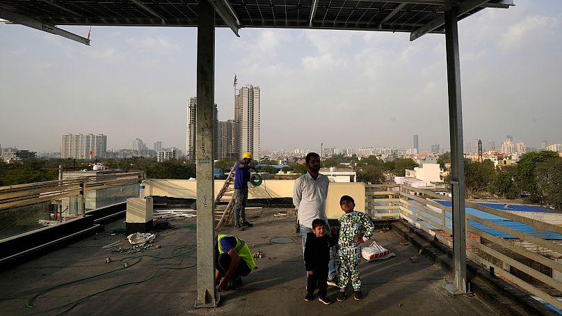 Children along with their father look at the newly installed solar panels on the roof of their house in Gurugram on the outskirts of New Delhi.