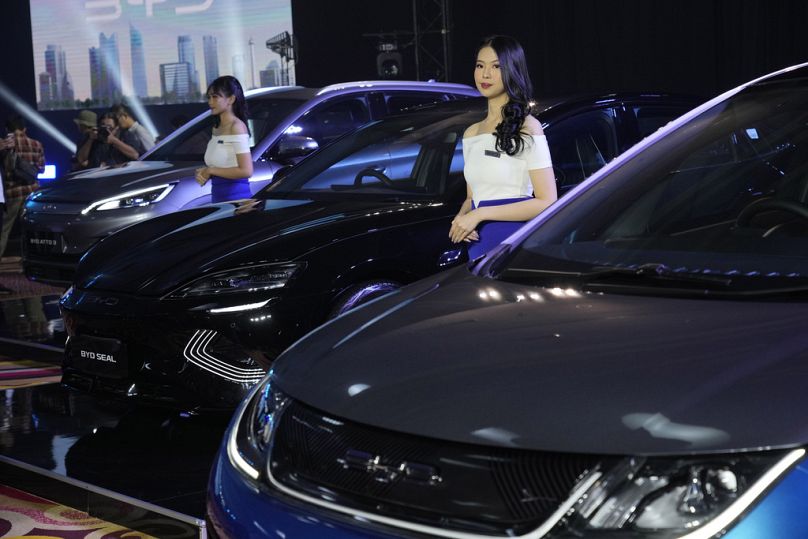 Models stand near BYD electric cars on display during their launch event in Jakarta, January 2024