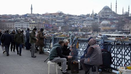 People warm themselves with a fire while fishing over the Galata bridge in Istanbul, Turkey. Feb. 21, 2024. 
