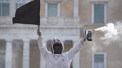 Ein Imker hält während einer Demonstration vor dem griechischen Parlament in der Innenstadt von Athen, Griechenland, am Donnerstag, dem 22. Februar 2024, eine schwarze Flagge.