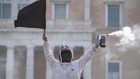 Ein Imker hält während einer Demonstration vor dem griechischen Parlament in der Innenstadt von Athen, Griechenland, am Donnerstag, dem 22. Februar 2024, eine schwarze Flagge.