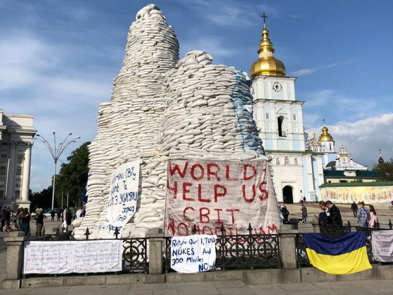 Sandbags cover monuments in Kyiv to protect them from Russian shelling. Residents have added signs with call for helps and Ukrainian flags.