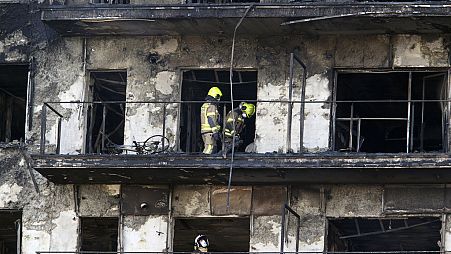 Firefighters remove a charred body inside a burned block building in Valencia, Spain, Friday, Feb. 23, 2024. 