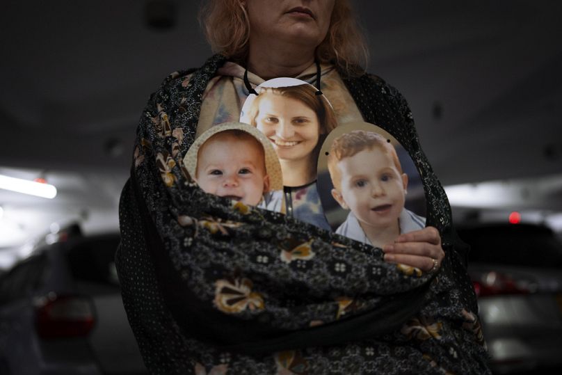A woman holds a mask depicting the faces of Shiri Bibas and her sons Kfir and Ariel, Israelis held hostage by Hamas, during a protest in Tel Aviv, February 2024
