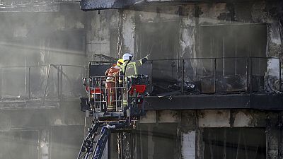 Firefighters work at a burnt out residential building in Valencia, Spain, Friday, Feb. 23, 2024.