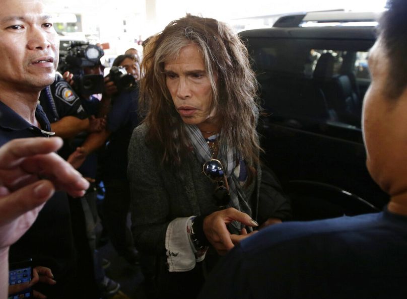 Steven Tyler of the famed Aerosmith rock band gestures before boarding his waiting van upon arrival from Melbourne Sunday May 5, 2013 in Manila, Philippines.