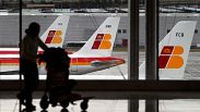 Iberia-Flugzeuge sind in einer Parkzone zu sehen, während ein Passagier sein Gepäck trägt.