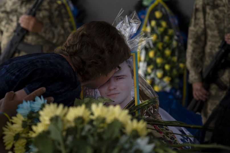 Zynaida Nedoleshko kisses the photo of her nephew, Roman Shadlovskyi, during a reburial service for him in Bucha, July 2023