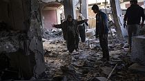 Civili a a Gaza tra le rovine di quello che rimane di un'abitazione