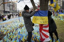 متطوع ياباني يعلق علم أوكرانيا على شجرة في ساحة ميدان بالعاصمة كييف في الذكرى الثانية للحرب الروسية الأوكرانية