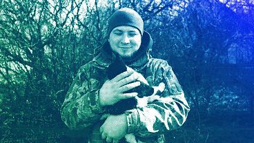 Andrii, 25, a Ukrainian commander of Grad crew, pets a cat, while waiting for orders from command centre at the frontline in Donetsk region, February 2024