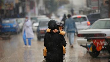 أم فلسطينية تحمل ابنها في أحد شوارع قطاع غزة حيث يعيش الناس على حافة المجاعة وترقبا لاجتياح عسكري لرفح