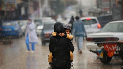 أم فلسطينية تحمل ابنها في أحد شوارع قطاع غزة حيث يعيش الناس على حافة المجاعة وترقبا لاجتياح عسكري لرفح
