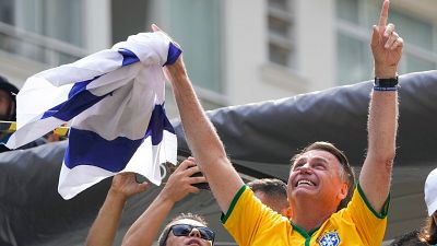 جايير بولسونارو، الرئيس السابق للبرازيل، يرفع علم إسرائيل في أثناء خلال مظاهرة مع أنصاره في ساو باولو