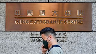 A man walks past the entrance of the headquarters of China Evergrande Group in Hong Kong Monday, Oct. 4, 2021. 