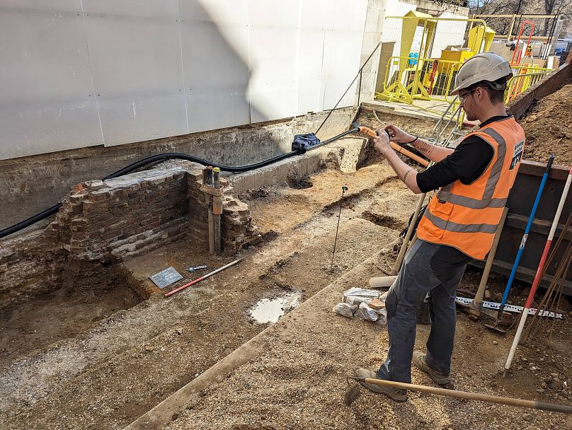 Ein Archäologe fotografiert einen Teil der Ausgrabung, darunter ein Fragment der nachmittelalterlichen Mauer.