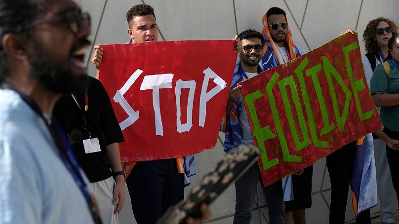 Demonstrators hold signs that read "stop ecocide" at the COP28 UN climate summit in Dubai, December 2023.