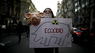 Женщина держит плакат с надписью на испанском языке «Экоцид»