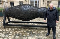 Ukraine's Mikhail Reva poses next to one of his art pieces, 22 February 2024, in Paris.