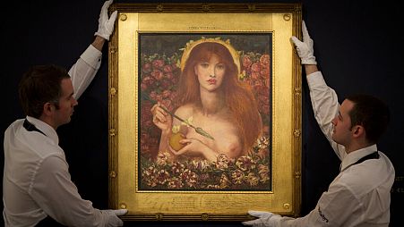 Sotheby's auction house employees pose for photographs with the Dante Gabriel Rossetti watercolor "Venus Verticordia" at their premises in London, Friday, Dec. 5, 2014.