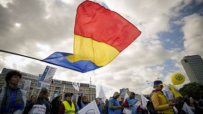 Manifestanti e sindacalisti sventolano la bandiera rumena davanti alla sede del governo a Bucarest chiedendo aumenti di stipendi e pensioni (20 ottobre 2022)